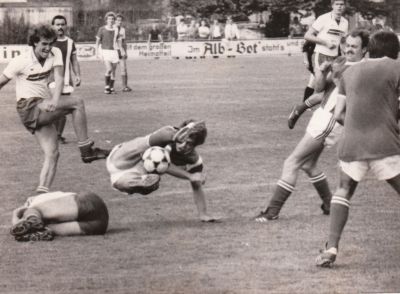 Saison 1985/86
Heimspiel gegen den SV Karsau. Bartram zieht ab, ein Gegenspieler wirft sich entgegen. Ein VfBler igelt sich zusammen. Aus dem Bild laufend VfB-Spieler M. Ruppelt.
